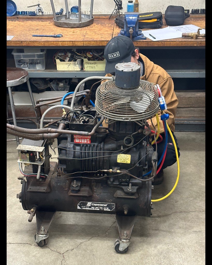 Student working on commercial refrigeration compressor equipment in the HVAC School lab